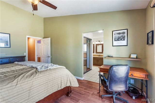 bedroom with baseboards, a ceiling fan, lofted ceiling, ensuite bath, and light wood-type flooring