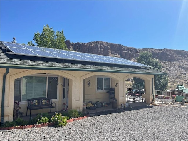 2405 N Clack Canyon Rd, Kingman, AZ 86409 - view of front of house with a mountain view, roof mounted solar panels, stucco siding, and a porch