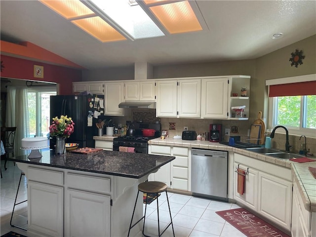 2405 N Clack Canyon Rd, Kingman, AZ 86409 - kitchen featuring black appliances, under cabinet range hood, light tile patterned floors, white cabinetry, and lofted ceiling