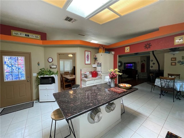 2405 N Clack Canyon Rd, Kingman, AZ 86409 - kitchen featuring light tile patterned flooring, a breakfast bar area, black microwave, white cabinets, and dark stone countertops
