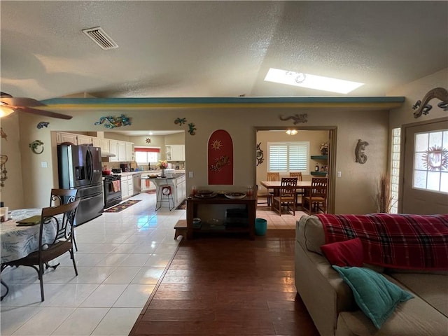 2405 N Clack Canyon Rd, Kingman, AZ 86409 - living area featuring a textured ceiling, ceiling fan, vaulted ceiling, a skylight, and light wood-type flooring