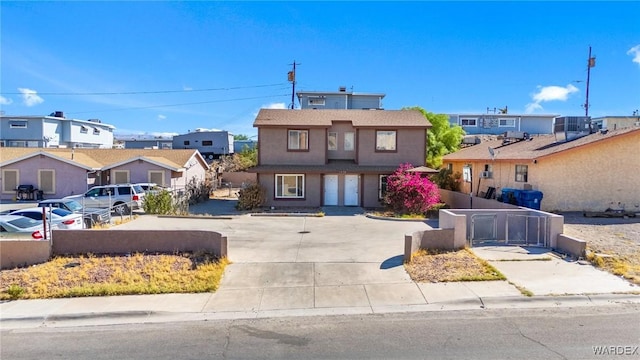 view of front facade featuring fence, a residential view, and stucco siding