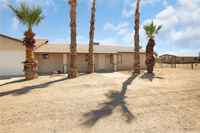 view of front of property featuring an attached garage, fence, and stucco siding