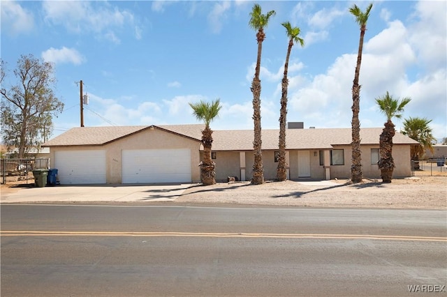 view of front facade featuring driveway, an attached garage, fence, and stucco siding