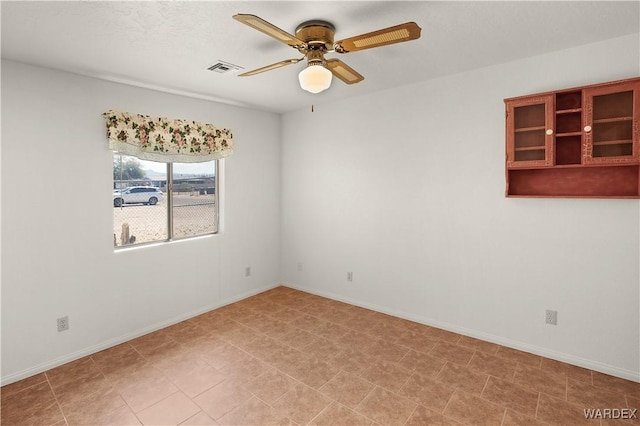 spare room featuring baseboards, visible vents, and a ceiling fan