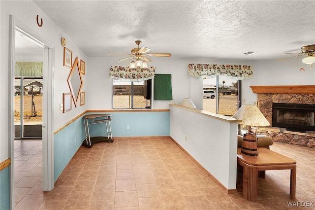 kitchen with ceiling fan, a textured ceiling, a fireplace, and tile patterned flooring