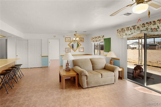 living room featuring a textured ceiling, visible vents, and a ceiling fan