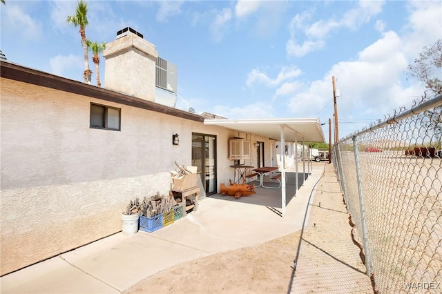 rear view of house featuring a chimney, a patio area, fence private yard, and stucco siding