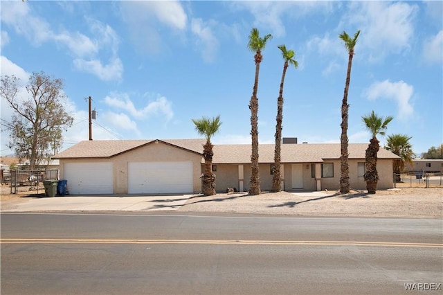 view of front facade with an attached garage, fence, concrete driveway, and stucco siding