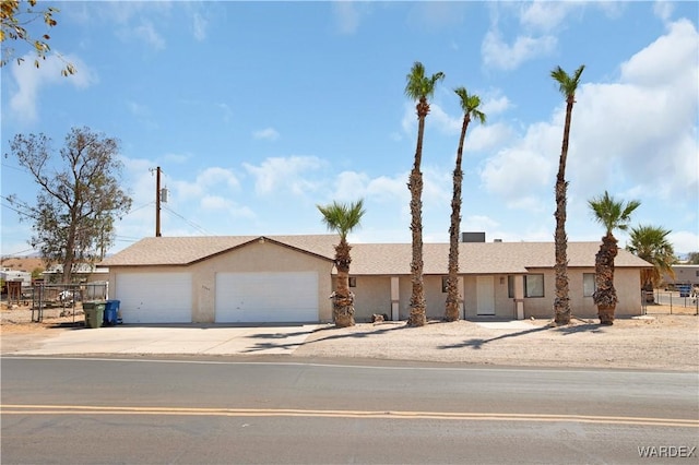 view of front of property featuring a garage, driveway, fence, and stucco siding