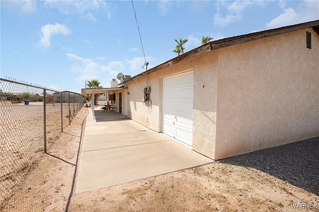 view of home's exterior with a garage, fence, and stucco siding