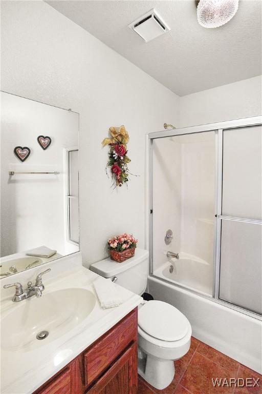 full bathroom featuring shower / bath combination with glass door, visible vents, toilet, vanity, and tile patterned floors