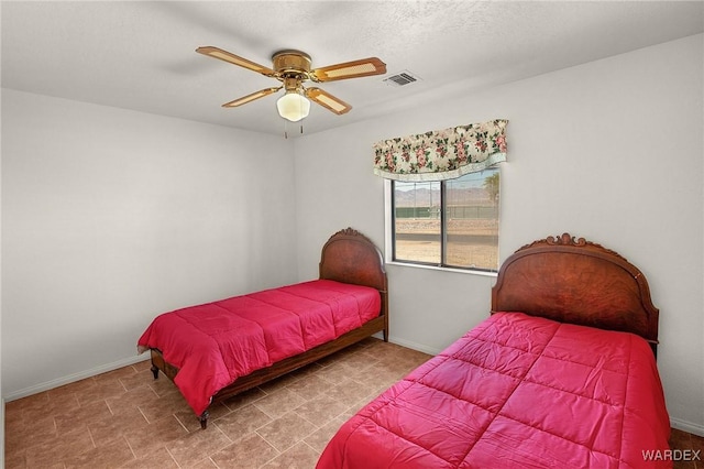 bedroom with baseboards, a textured ceiling, visible vents, and a ceiling fan