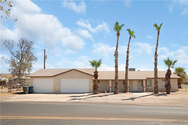 ranch-style home with a garage, driveway, fence, and stucco siding