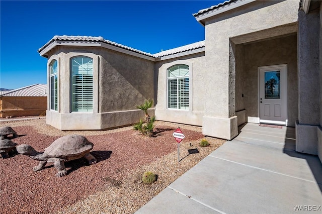 view of home's exterior with a tile roof and stucco siding