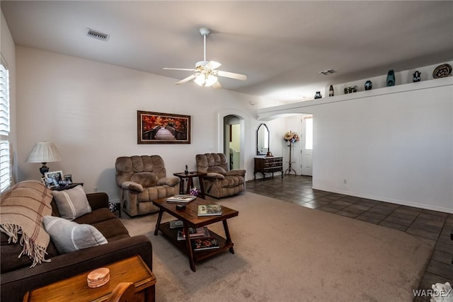 living room featuring visible vents, arched walkways, ceiling fan, dark tile patterned floors, and dark carpet