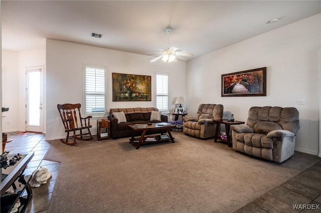 living area with a ceiling fan, visible vents, dark carpet, and dark tile patterned floors