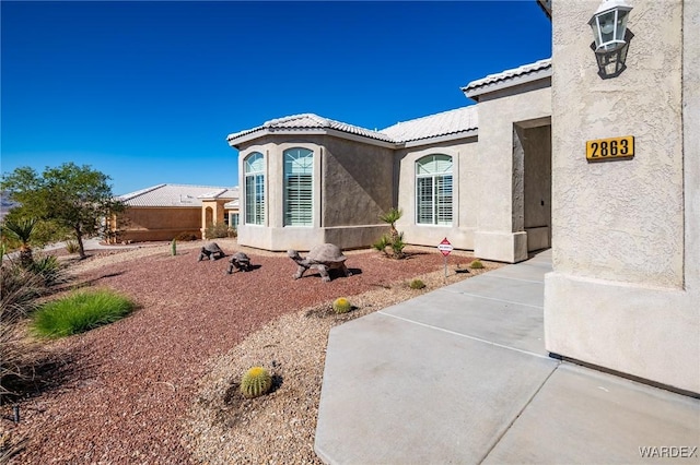 exterior space featuring a tiled roof, a patio area, and stucco siding