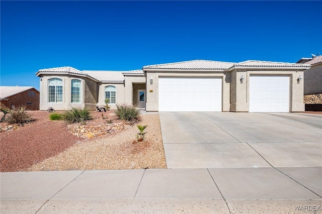 view of front of home with a garage, concrete driveway, a tiled roof, and stucco siding