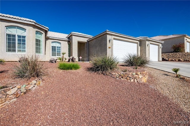 view of front facade with a garage, concrete driveway, a tiled roof, and stucco siding