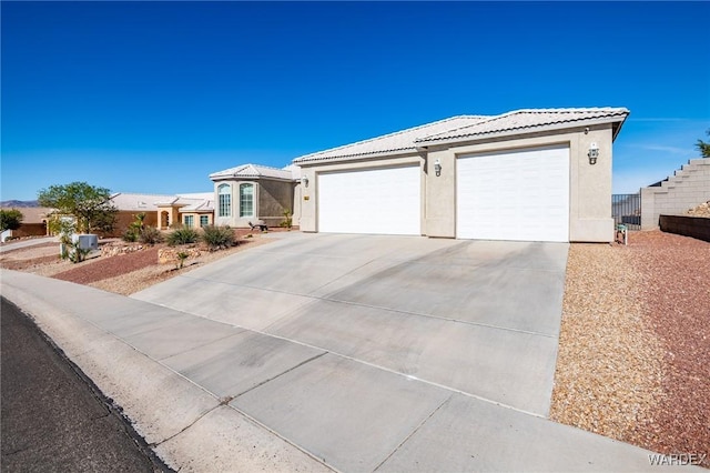 single story home featuring a garage, driveway, a tiled roof, and stucco siding