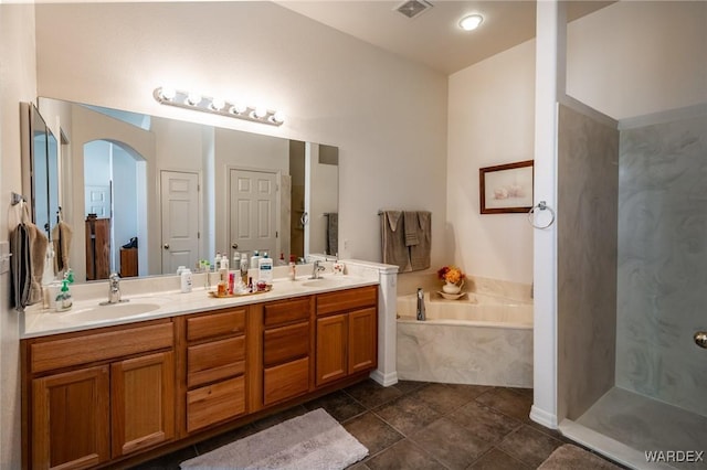 bathroom with double vanity, a garden tub, visible vents, and a sink