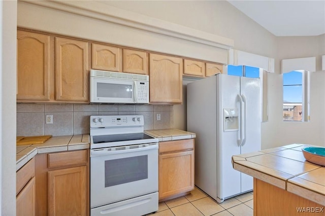 kitchen with tile countertops, light brown cabinetry, and white appliances