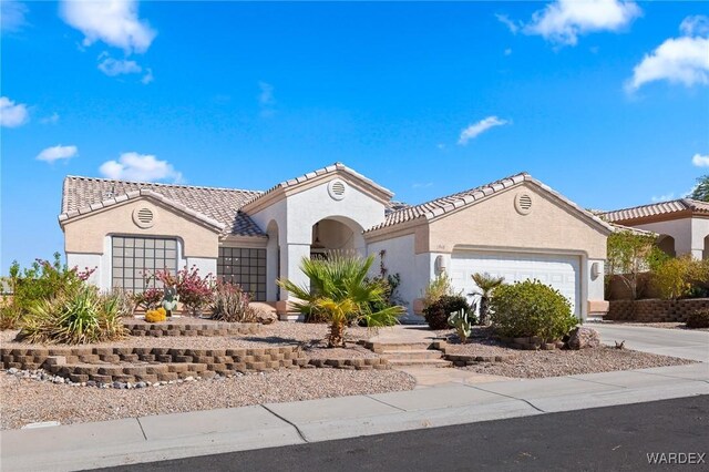 mediterranean / spanish home featuring an attached garage, a tile roof, concrete driveway, and stucco siding