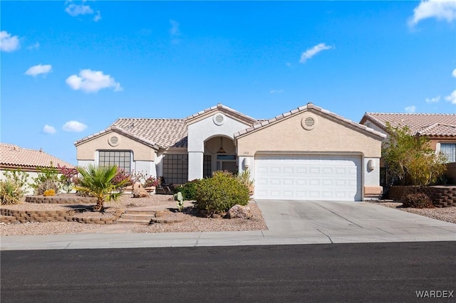 mediterranean / spanish-style home with an attached garage, a tile roof, concrete driveway, and stucco siding