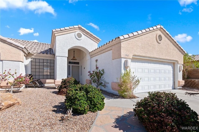 mediterranean / spanish house featuring a garage, concrete driveway, and stucco siding