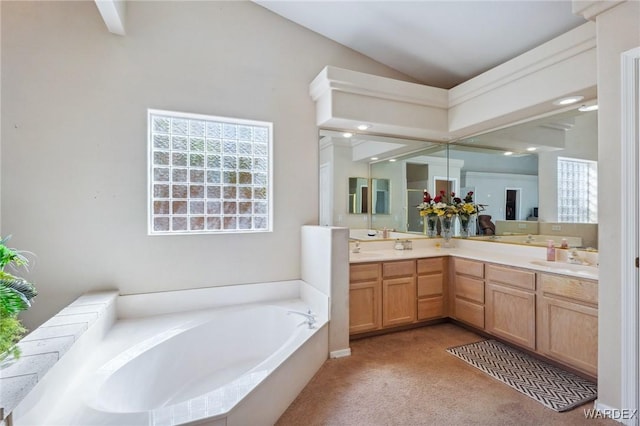 bathroom with lofted ceiling, a garden tub, a sink, and double vanity