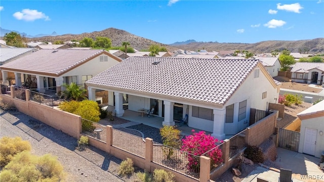 rear view of house featuring a fenced front yard, a residential view, a tile roof, and a mountain view