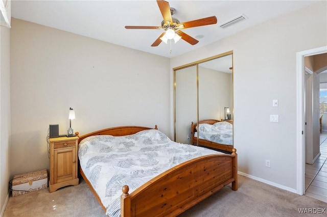 bedroom featuring light carpet, baseboards, visible vents, ceiling fan, and a closet