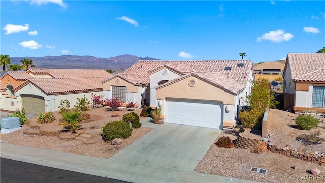 view of front of house featuring driveway, a tile roof, an attached garage, a mountain view, and stucco siding