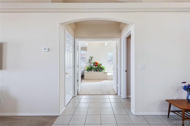 interior space featuring arched walkways, light tile patterned flooring, and baseboards