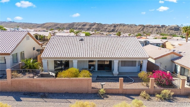 view of front of home featuring a fenced front yard, a tile roof, a residential view, and a mountain view