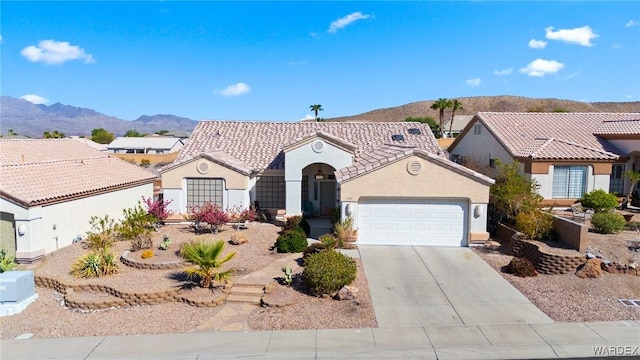 mediterranean / spanish house featuring driveway, a tile roof, an attached garage, a mountain view, and stucco siding