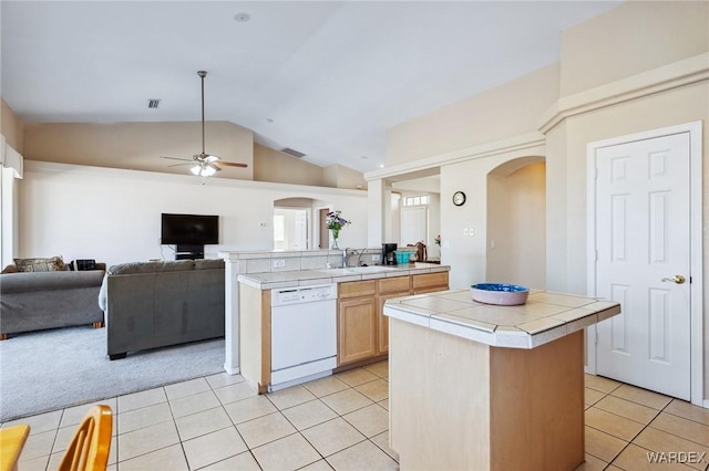 kitchen featuring tile countertops, light tile patterned floors, arched walkways, white dishwasher, and open floor plan