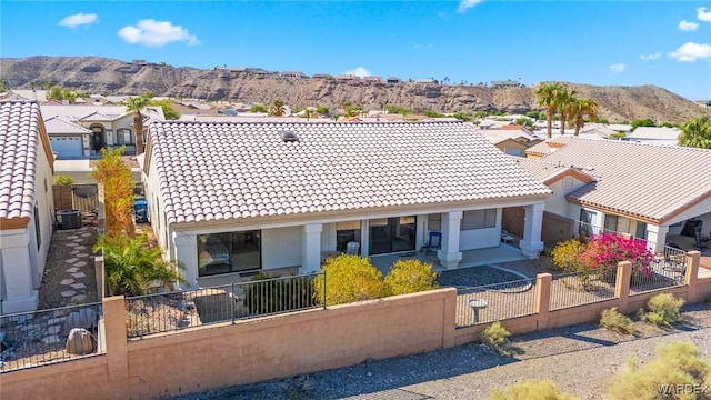 exterior space featuring a tiled roof, a fenced front yard, a residential view, and a mountain view