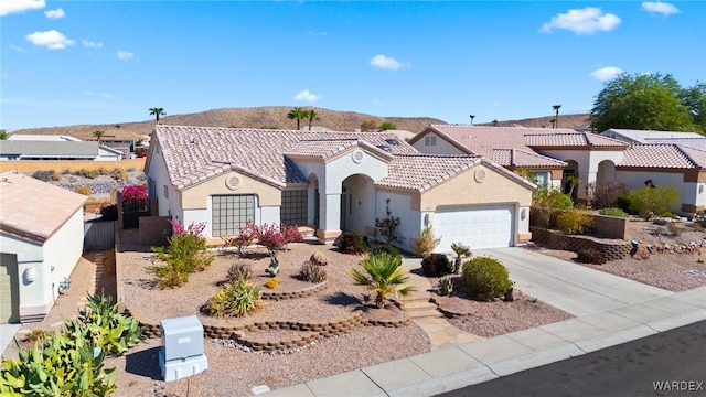 mediterranean / spanish house with a tile roof, stucco siding, an attached garage, a residential view, and driveway