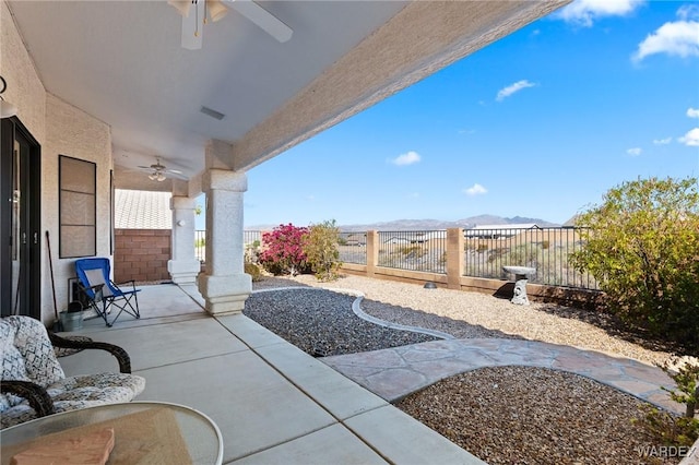 view of patio with a fenced backyard, ceiling fan, visible vents, and a mountain view