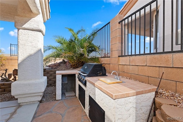 view of patio with a sink, an outdoor kitchen, area for grilling, and fence