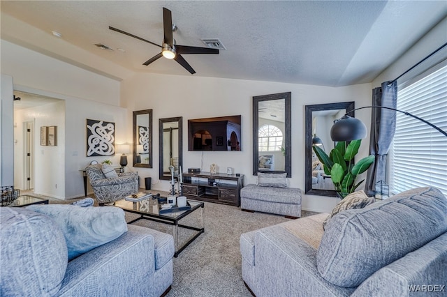 living area featuring lofted ceiling, light colored carpet, visible vents, ceiling fan, and a textured ceiling