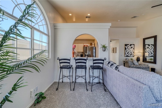 carpeted dining area with arched walkways, visible vents, and baseboards