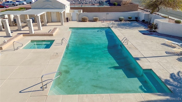 community pool featuring a patio area, a fenced backyard, and a hot tub