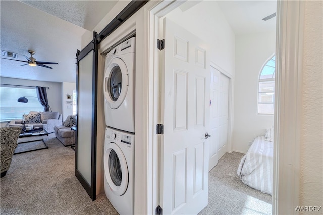 washroom featuring light colored carpet, plenty of natural light, visible vents, and stacked washing maching and dryer