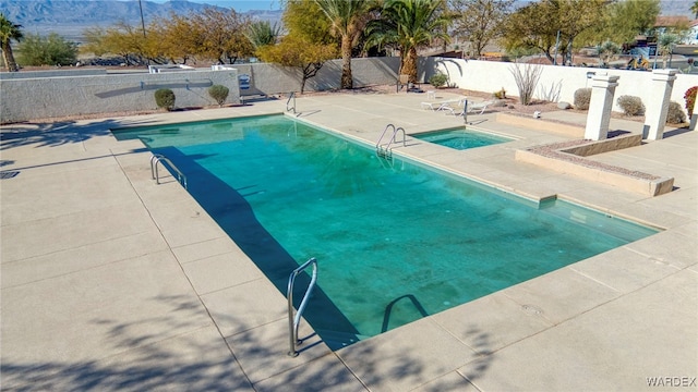 view of swimming pool with a fenced in pool, fence, and an in ground hot tub