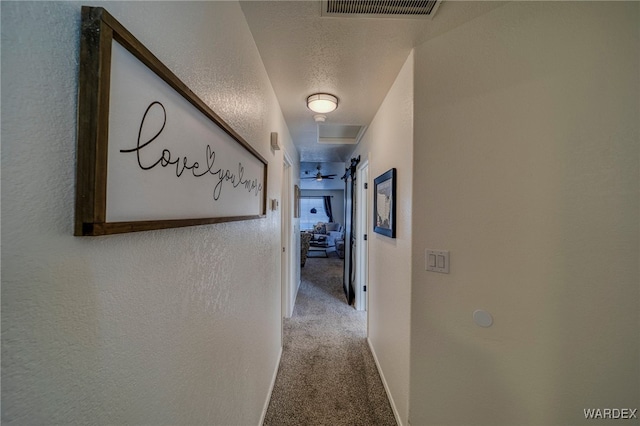 corridor with visible vents, a textured wall, carpet flooring, a textured ceiling, and baseboards