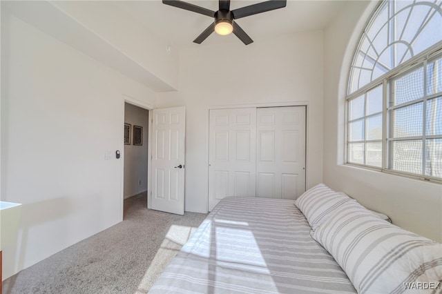 bedroom featuring light carpet, a ceiling fan, and a closet