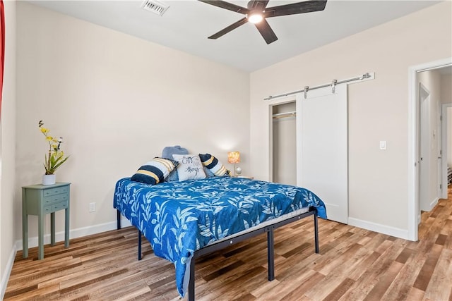 6183 S Lago Grande Dr, Fort Mohave, AZ 86426 - bedroom with a barn door, light wood-type flooring, baseboards, a closet, and ceiling fan